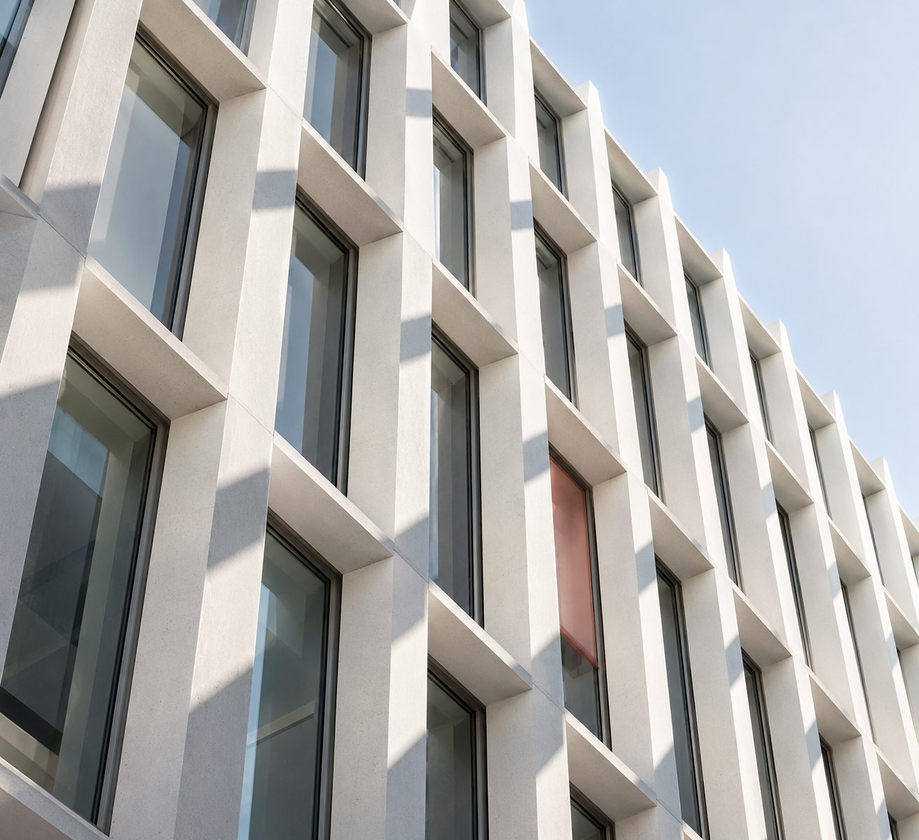 Moderne Fassade mit Betonlamellen und Glas, grafisches Spiel von Licht und Schatten